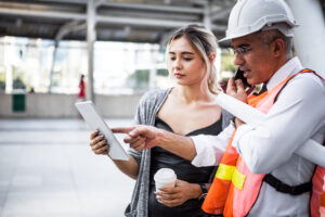 Senior engineers describe details of project to young woman customers at work site.